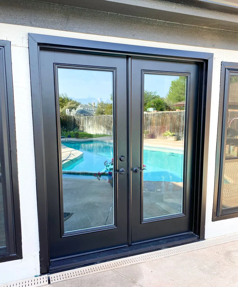 New black French doors opening onto a pool