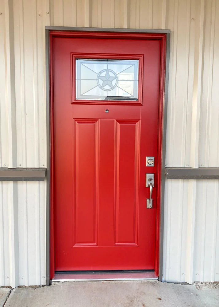 Red front door with a small decorative glass window