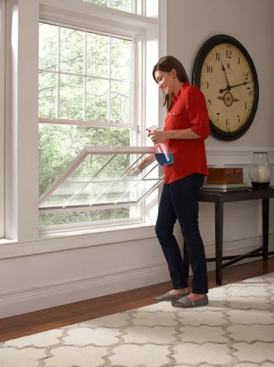 Woman standing by an open double-hung window in a living room