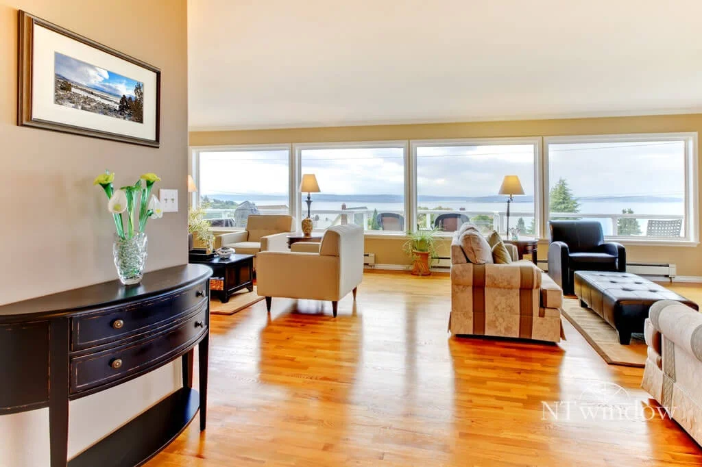 Bright living room with a row of large windows looking out over the water