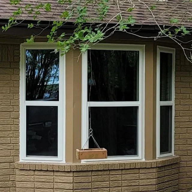 Three-sided bay window with white frames on a tan brick house