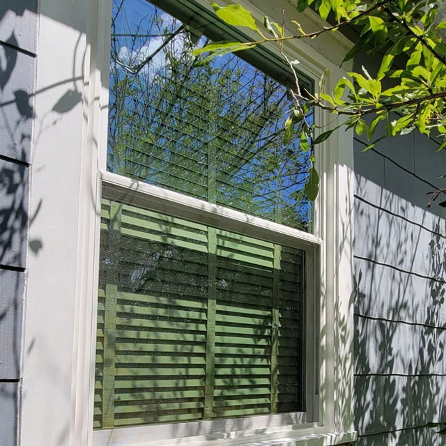 White double-hung window in a house with gray siding