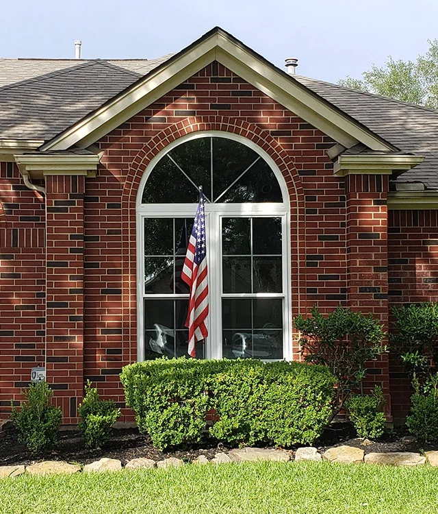Brick home with a tall arched window and an American flag