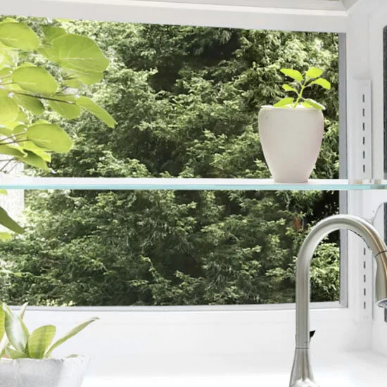 Garden window with a glass shelf and a potted plant above a kitchen faucet