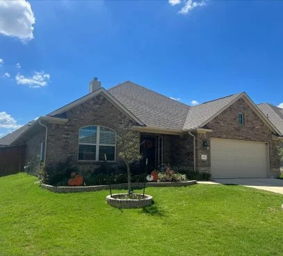 Brick one-story home with gutters, a two-car garage and a green lawn