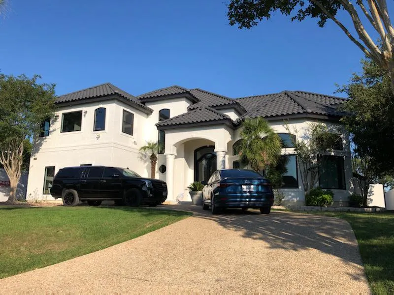 Two-story stucco home with new arched windows, seen from the driveway