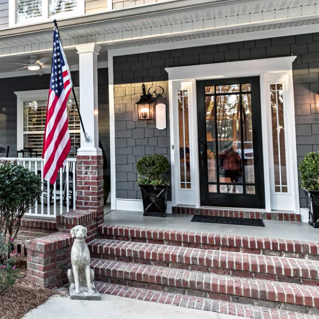 Brick front porch with an American flag and a glass front door