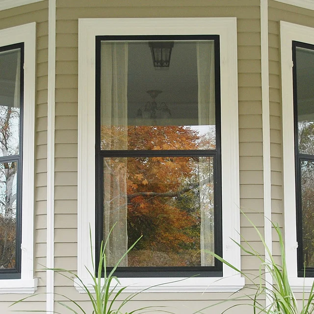 Black-framed window with white trim in a house with tan siding