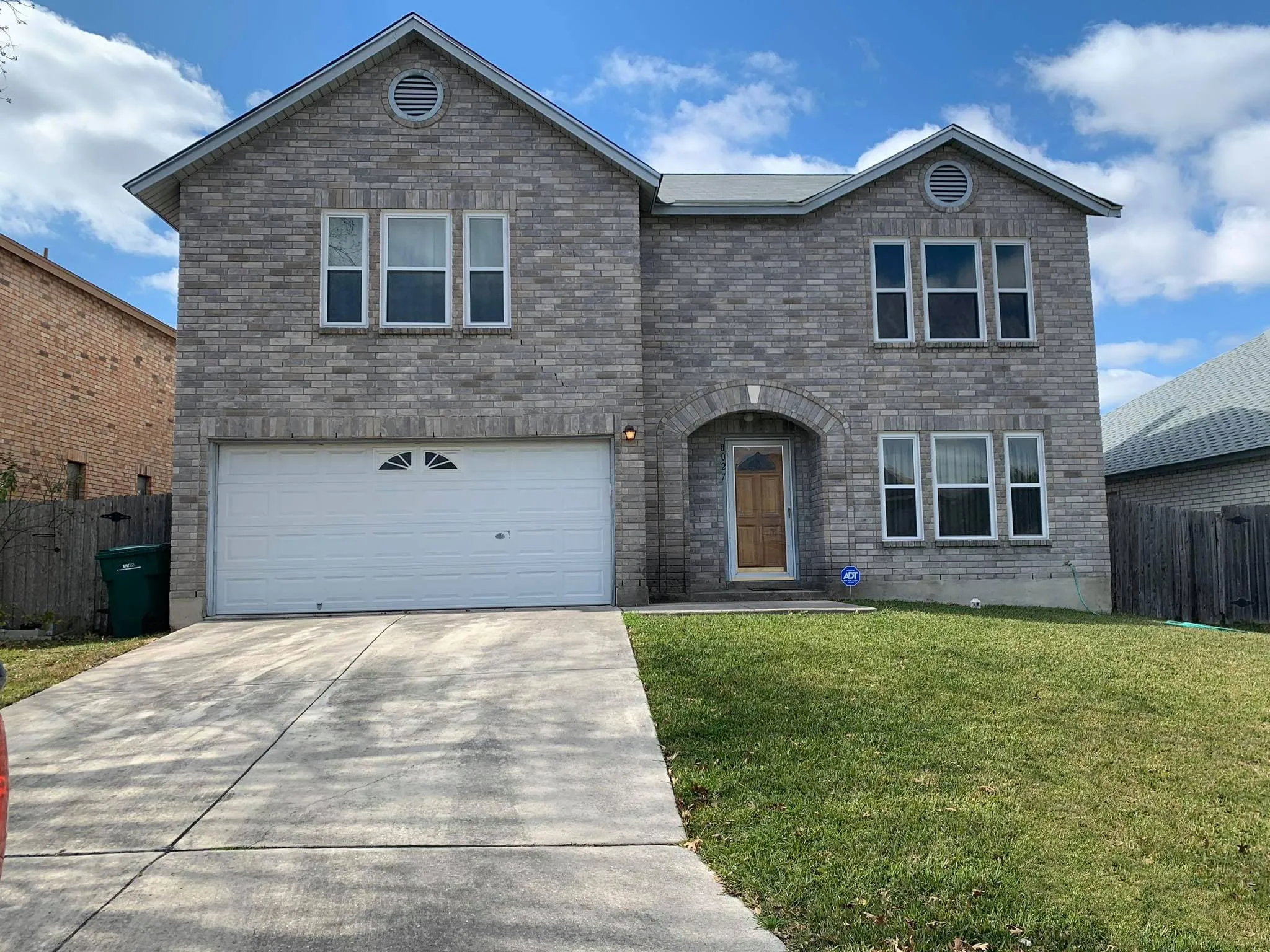 Two-story brick home with new windows above the garage