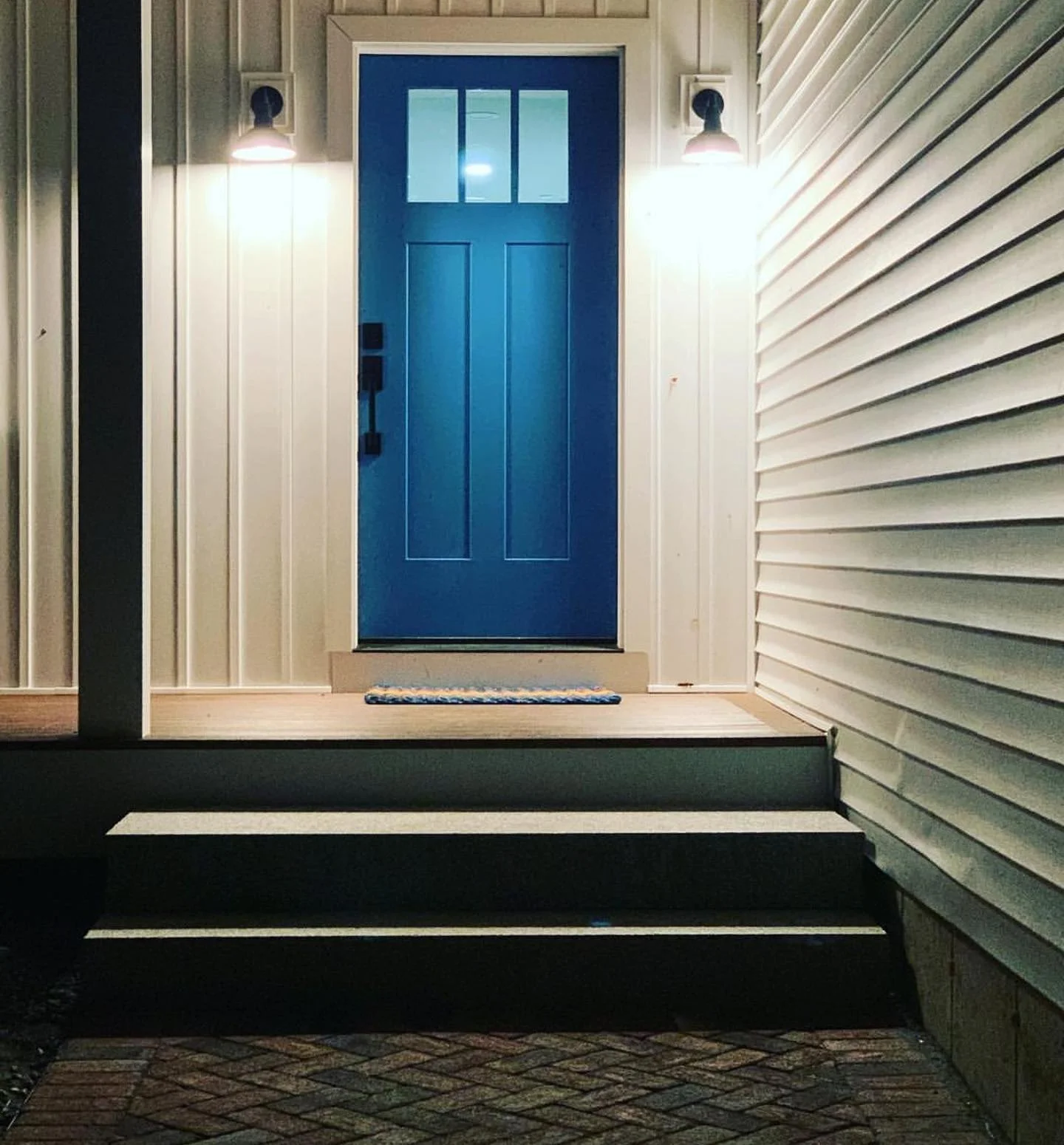 Blue front door with small glass lites at the top of dark steps