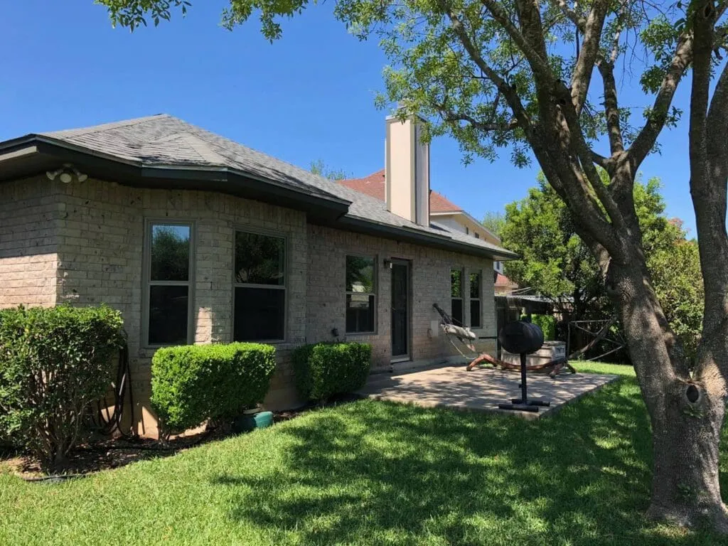Brick home with new windows beside a backyard patio
