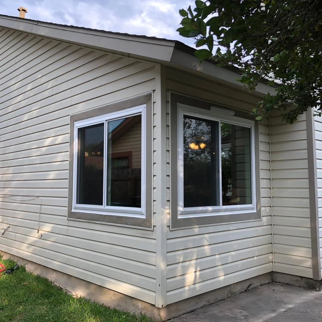 Corner of a house with vinyl siding and two new replacement windows