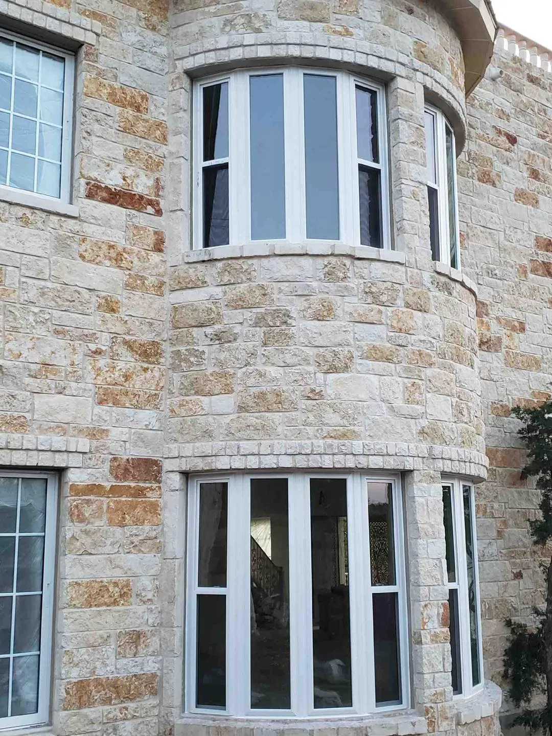 Stone home with a curved wall of new tall windows